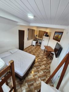 a bedroom with a bed and a kitchen with a table at Hospedaria Ilhabela - Flats Balsa in Ilhabela