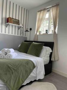 een bed met groene en witte lakens en een raam bij One bedroom Putney Village flat in Londen