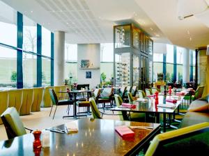 a restaurant with tables and chairs and windows at Pullman Paris Roissy Cdg Airport in Roissy-en-France