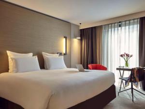 a large bed in a hotel room with a laptop on it at Pullman Paris Roissy Cdg Airport in Roissy-en-France
