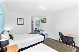 a hotel room with two beds and a table at Econo Lodge Waterford in Loganlea