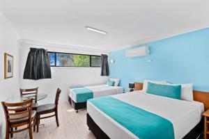 a hotel room with a bed and a table and chairs at Econo Lodge Waterford in Loganlea