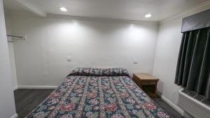 a bedroom with a bed with a floral bedspread at Airport Motel - Inglewood in Inglewood