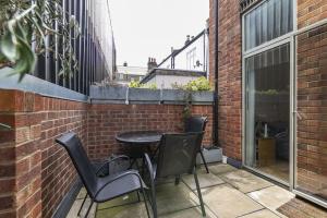 a patio with a table and chairs on a brick wall at Spitalfields Market Garden Flat in London