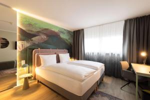 a bedroom with a bed and a painting on the wall at The Rilano Hotel München in Munich