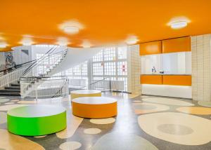 a lobby with orange and green tables and stairs at prizeotel Dortmund-City in Dortmund