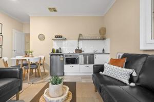 sala de estar con sofá negro y cocina en Marcotta Guest Suite - Moments to Golf Course en Orange