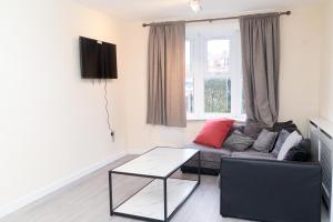 a living room with a couch and a table at Beautiful 5 single bedroom house in Dagenham