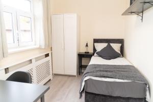 a bedroom with a bed and a desk and a window at Beautiful 5 single bedroom house in Dagenham