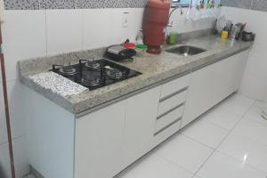 a kitchen counter with a stove and a sink at Casa dos Bento in Contagem