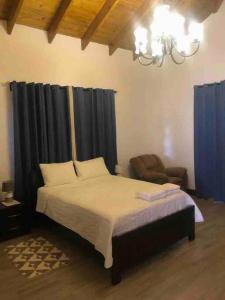 a bedroom with a bed and a chair and a chandelier at Rancho Ecoturistico Grevillea 