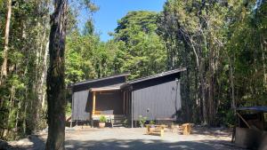 a black building in the middle of a forest at Cabaña Bosque Rio in Puerto Varas
