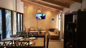uma sala de estar com uma mesa e uma televisão na parede em Cabaña Bosque Rio em Puerto Varas