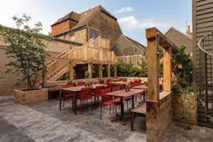 a patio with wooden tables and red chairs at The George In Rye in Rye
