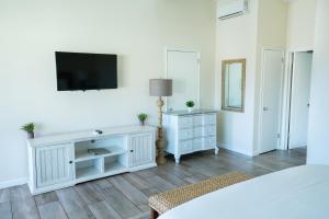 a bedroom with white furniture and a tv on a wall at Pacific Crest Hotel Santa Barbara in Santa Barbara