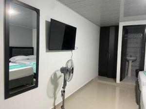 Habitación con ventilador y TV en la pared. en Hotel Dulces Sueños en Santa Rosa de Cabal