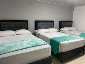 a room with three beds in a room at Hotel Dulces Sueños in Santa Rosa de Cabal