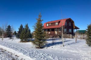 una casa en la nieve con un árbol delante en The Log Cabin, en Driggs