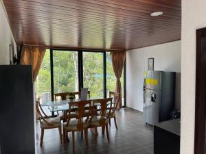 a dining room with a table and a refrigerator at Hermosa Cabaña cerca a Villeta in Quebradanegra