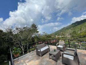 a balcony with chairs and a table and a mountain at Hermosa Cabaña cerca a Villeta in Quebradanegra