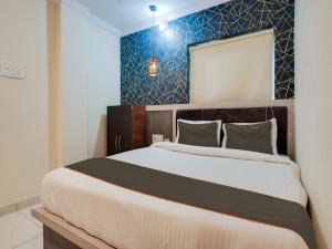 a bedroom with a large bed and a blue wall at Super Collection O Hotel Blue Petals in Shamshabad