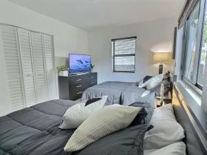 1 dormitorio con 2 camas con almohadas y TV en Jacuzzi•Glamping•Gym•Parking•BBQ•Soft Beds•Secure en Miami