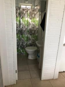 a bathroom with a toilet and a wall with plants at Hospedaria Mirante da maré ap2 in Imbituba