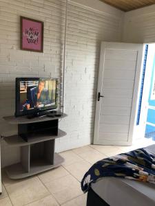 a bedroom with a tv and a bed and a door at Hospedaria Mirante da maré ap2 in Imbituba