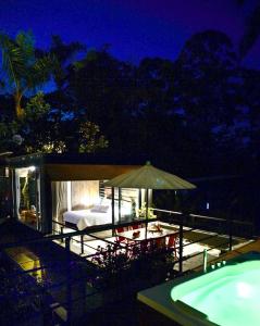 eine Terrasse mit einem Bett und einem Sonnenschirm neben einem Pool in der Unterkunft LALDEA Nirvana Eco Villa in Cerritos in Pereira