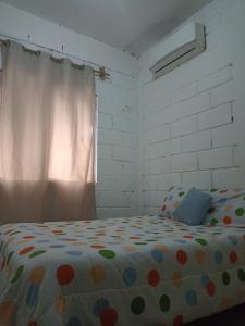 um quarto com uma cama com lençóis de bolinhas e uma janela em Casa Adelita em Barra de la Cruz
