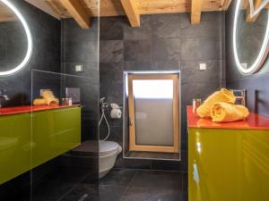 La salle de bains est pourvue de placards verts et jaunes et d'un miroir. dans l'établissement Nature Lodge Kaprun B, à Kaprun
