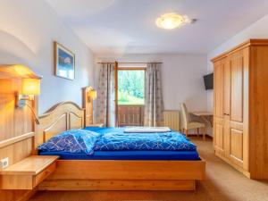 a bedroom with a bed and a desk and a window at Pension Blaiken XL in Scheffau am Wilden Kaiser