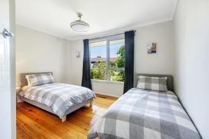 twee bedden in een kamer met een raam bij Sunlit Suburbia - A Breezy Abode in Glen Waverley in Glen Waverley