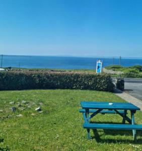 een blauwe picknicktafel in het gras bij de oceaan bij The Ramblers Rest B&B in Doolin