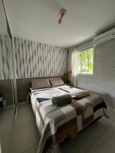 1 dormitorio con 1 cama con manta a rayas y ventana en Apartamento GolfVille Residence en Aquiraz