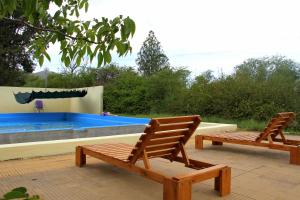 2 sillas de madera sentadas junto a una piscina en Cabañas Bhakti Dham, hospedaje vegetariano en San Esteban