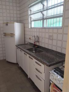 La cuisine est équipée d'un évier et d'un réfrigérateur blanc. dans l'établissement Casa Harmonia, à Guarujá