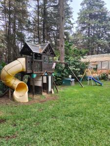 einen Spielplatz mit einem Haus und einer Rutsche in der Unterkunft San Marino grupos familiares o amigos in San Francisco Tlalnepantla