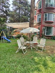 einen Tisch und Stühle mit Sonnenschirm und Spielplatz in der Unterkunft San Marino grupos familiares o amigos in San Francisco Tlalnepantla