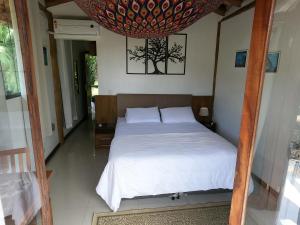 a bedroom with a white bed with a chandelier at Chalé e Suite Manacá in Ubatuba