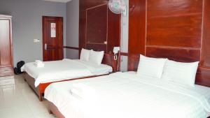 Bình Minh Hotel في مدينة هوشي منه: سريرين في غرفة الفندق ذات شراشف بيضاء
