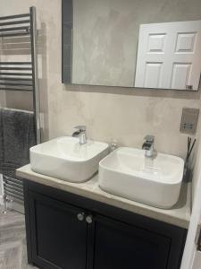een badkamer met 2 witte wastafels en een spiegel bij Luxurious New Serviced Apartment (Surrey) in Redhill