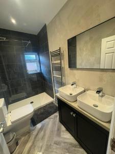 een badkamer met 2 wastafels, een toilet en een douche bij Luxurious New Serviced Apartment (Surrey) in Redhill