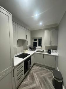 een kleine keuken met witte kasten en een wastafel bij Luxurious New Serviced Apartment (Surrey) in Redhill