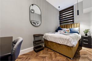 a bedroom with a bed with a mirror and a chair at Lovely 2 BR with Grill in London