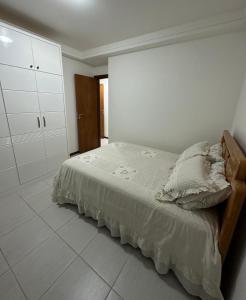 a bedroom with a bed and a white wall at Enseada Azul - Apto 150m da Praia de Peracanga in Guarapari
