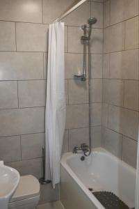 La salle de bains est pourvue d'une baignoire, de toilettes et d'une douche. dans l'établissement 2 bedroom apartment with balcony near Tottenham Hostpur Stadium, à Edmonton