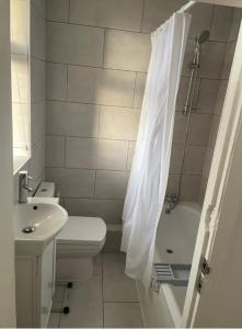 a bathroom with a toilet sink and a shower curtain at 2 bedroom apartment with balcony near Tottenham Hostpur Stadium in Edmonton
