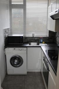 uma cozinha com uma máquina de lavar roupa e um lavatório em 2 bedroom apartment with balcony near Tottenham Hostpur Stadium em Edmonton