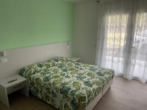 una camera con un letto con copriletto verde e bianco di Il Fiore del lago a Pacengo di Lazise
